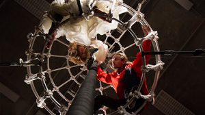 Photograph shot frm under two performers suspended by rope and hoop