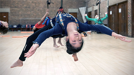 Young girl suspended from harness, floating on her back above the floor.