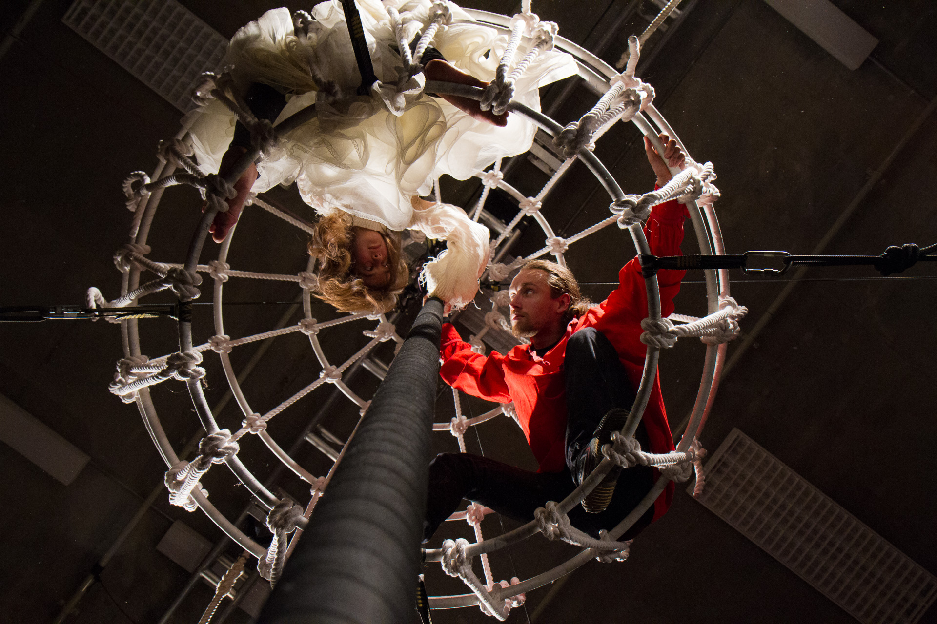 Be-loved performers in the centre of a rope cage, suspended around a chinese pole.