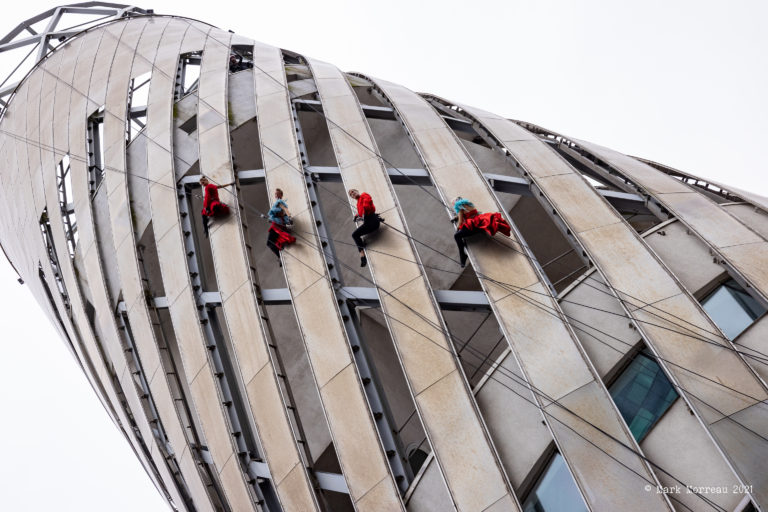 Four aerial performers suspended from top of tall building