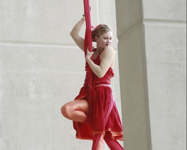 Performer in red flowing costume holding on to red silk.