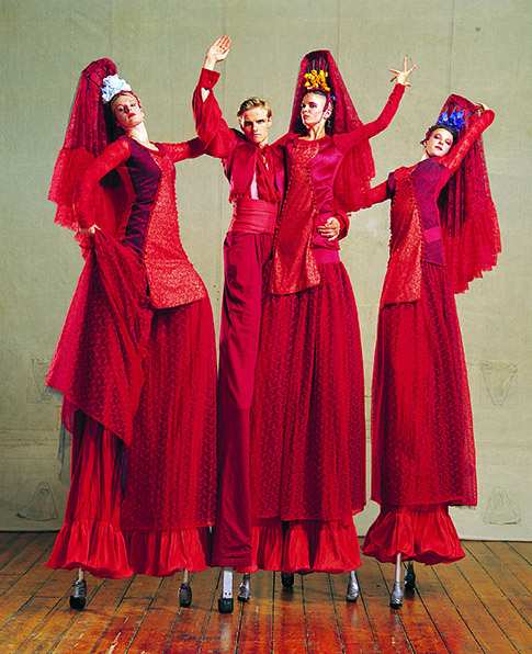 Four performers in red flamenco dresses on stilts