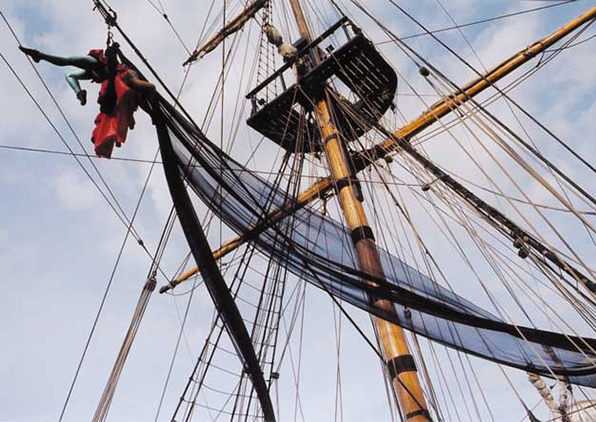 Aerial performer in red, suspended in sail of Cutty Sark hip